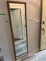 Full view of the framed mirror leaning against a wall showing size and shape