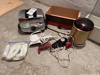 Overview of vintage small appliances including Sunbeam toaster, Gillette styler, Wahl massager, and brass lamp with cords and packing materials visible.