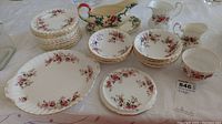 Overview of entire china set including plates, bowls, cream pitchers, gravy boat and serving plate all with floral lavender rose pattern and gold accents.