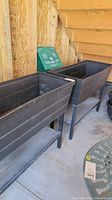 Two rectangular raised planters on stands seen under a staircase, showing overall appearance.