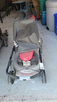 Front view of mower showing deck, wheels, handle, grass catcher bag
