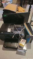 Photo showing HP printer/scanner, 26 inch monitor, file folders, and other miscellaneous items