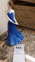Royal Doulton Alexandra figurine showing front view of woman in blue gown with folded hands.