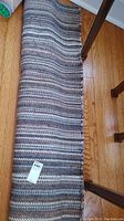 Full length view of the woven rug running under furniture showing its color and pattern details in blue and earth tones.