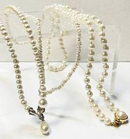 Photo showing two costume pearl necklaces, one with round pearls and a teardrop pendant, the other with irregular pearls and a vintage clasp.