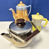 Photo showing all three items: stainless steel teapot, ceramic teapot, and yellow espresso stove pot.