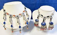 Two Tibetan silver stone beaded chokers displayed on white necklace busts against blue fabric background, showing front and angled views.