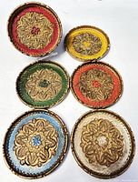 Top view of six carved Florentine coasters showing vibrant colors and intricate raised gold floral patterns.