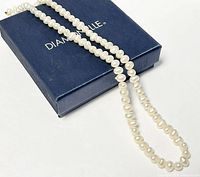Full view of the baroque pearl necklace on a DIAMONELLE blue box showcasing the length and the irregular shape of the pearls.