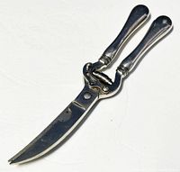 Full view of chicken bone cutters showing sterling silver handles and serrated curved blade