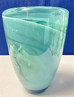 Front angle view of the swirled glass vase showing green/aqua hues and Kosta Boda sticker.