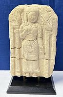 Front view of the sandstone wall fragment showing the carved female figure and decorative columns.