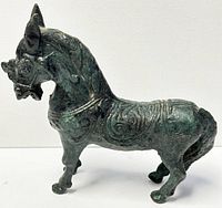 Side angle of the old Chinese bronze horse figurine showing detailed mane and body ornamentation with patina