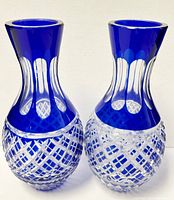 Front view of the pair of cobalt blue to clear cut crystal bud vases showing the intricate lattice cut pattern on the bulbous bases and clear elongated oval cuts on the necks.