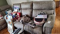 Front view of three-seat recliner sofa with items on seat