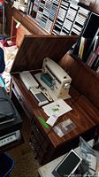 Fold-away wood table opened to reveal beige Kenmore sewing machine with manual and accessories on top.