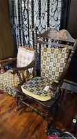 Photo showing both wooden rocking chairs side by side on wood floor, one with black and floral quilted cushion, the other with beige tufted cushion and fabric covers on arms.