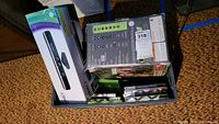 Boxed Xbox 360 Elite console and packed bundle box with games and Kinect sensor box on carpeted floor.
