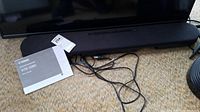 Yamaha ATS-1080 sound bar with tangled cables and owner's manual on carpeted floor.