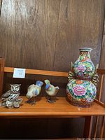 Shelf display of three bird figurines and one ornate Chinese vase, showing overall set