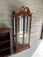Full view of ornate wooden display case with glass front and side panels, showing overall condition and design details.