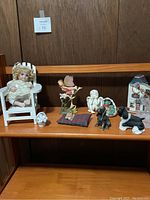 Front view of all knickknacks displayed on two wooden shelves with a wood paneled background.