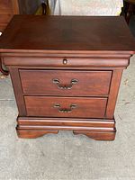 Front view of one nightstand showing two full-width drawers with brass bail pulls and shallow top drawer with round knob