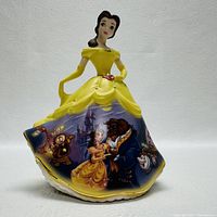 Front view of the Belle figurine in yellow gown with detailed images of Beauty and the Beast characters on the skirt.