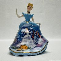 Porcelain Cinderella figurine bell featuring detailed painted skirt scenes from the Cinderella story and raised figure.