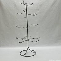 Full view of metal Christmas tree ornament holder with circular base and multiple branches for hanging.