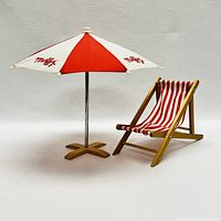 Miniature beach chair and umbrella set against a plain background to show details of fabric and construction