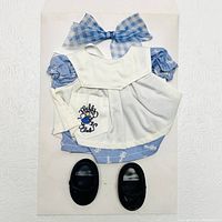 Top view of the Muffy VanderBear outfit including dress, apron, bow, and black shoes laid out flat on a white surface.
