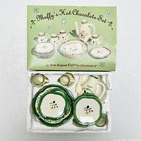 Full boxed set showing the Muffy's Hot Chocolate Set box with New England Country Christmas theme and all ceramic pieces inside including teapot, creamer, sugar bowl, cups, and plates.