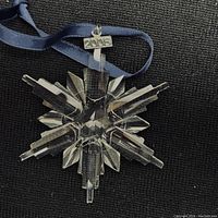 Crystal snowflake ornament with metal '2006' tag and navy ribbon on black background