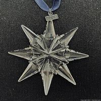 Close-up photo of clear faceted crystal star-shaped Christmas ornament with small metal 2009 tag attached to blue ribbon