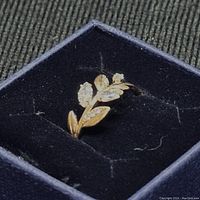 Gold-tone Swarovski ring with clear crystal leaves and petals in a floral design, shown in black velvet box.