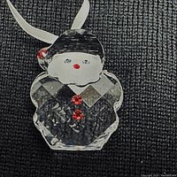 Close-up of the clear faceted crystal Santa Claus ornament with red and blue crystal accents on a textured fabric background, highlighting details and the hanging ribbon.