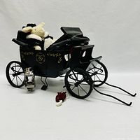 Photo of the black miniature VanderHare carriage with small tear in roof, soft toy lamb inside, silver decorative lantern, and red/white soft accessory.