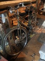 Full left-front view of green Raleigh bicycle leaning against wood wall