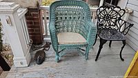Photo showing a light blue wicker chair and a black metal chair on porch floor next to a shoe brush.