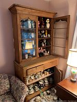 Full front view of two-piece china cabinet with glass door closed, showing overall form and finish