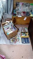 Overview of the craft supplies lot including basket, yarn, needles, magazines, scissors, and hoops
