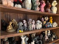 Image showing 19 various dog-themed figurines on wooden shelves including poodles and other dog breeds.
