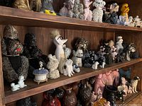 Wide view of shelves containing many dog figurines in ceramic and porcelain, various colors and sizes.