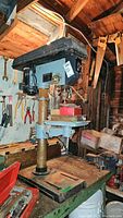 Front and side views of Delta 14 drill press showing overall structure, motor housing, base and table with attached red toolbox and wood block.