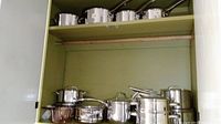 Overview of two cabinet shelves showing top row of saucepans and lower row of mixed pots