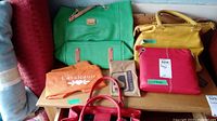 Five purses arranged on a low table with two dust bags visible - orange labeled Cavallanti and brown labeled Soprano