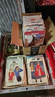 Large bin showing a variety of vintage sewing pattern envelopes from Butterick, Simplicity, McCall's, and Burda with multiple sizes and styles visible.