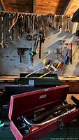 View of wall-mounted hand tools including wrenches, screwdrivers, and pliers along with green toolbox on bench