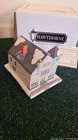 Front and side view of the Hawthorne 'The Antique Shop' Christmas village sculpture with original packaging and certificate.